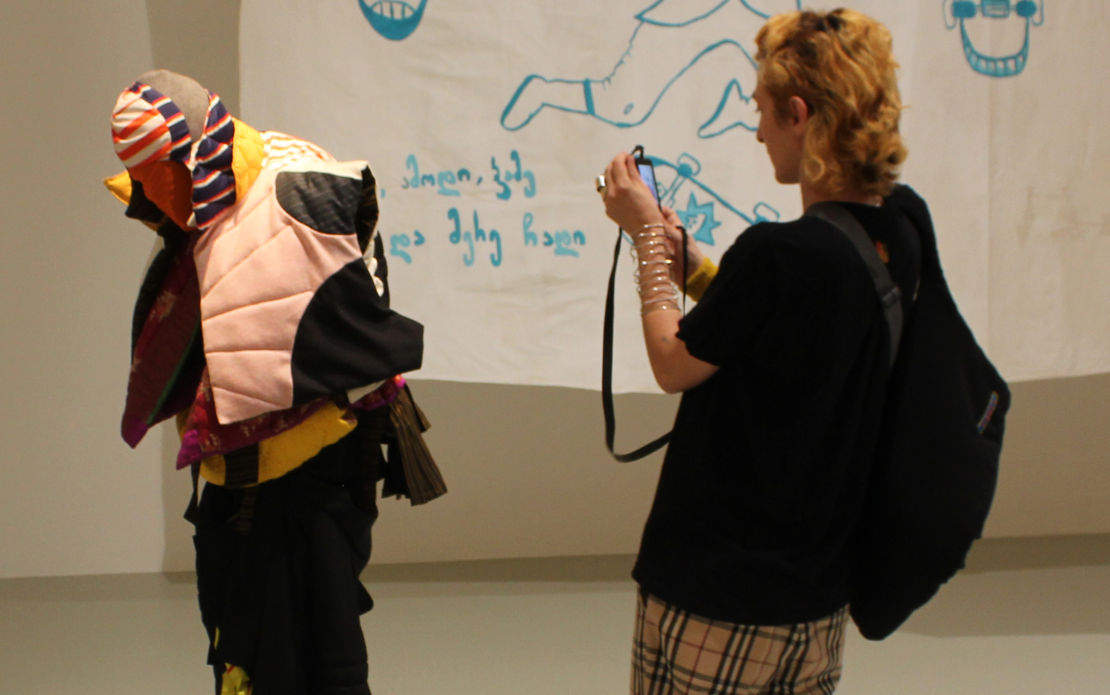 Tamuna Karumidze fotografiert ihr maschinell bewegtes Model mit der von ihr gestalteten Kleidung (Modelabel Tamra), Hauptraum der Ausstellung Lara protects me des museumangewandtekunst Frankfurt am Main, Foto von Kirsten Kötter